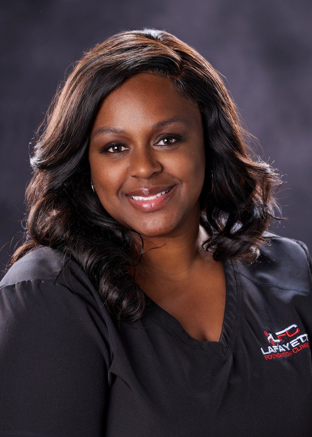 A woman in a black scrub top is smiling for the camera.