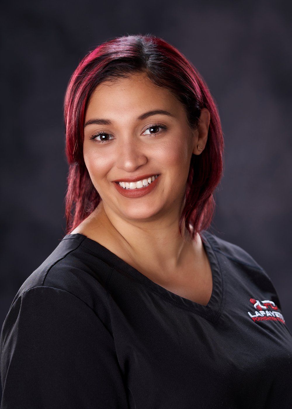 A woman with red hair is wearing a black shirt and smiling.