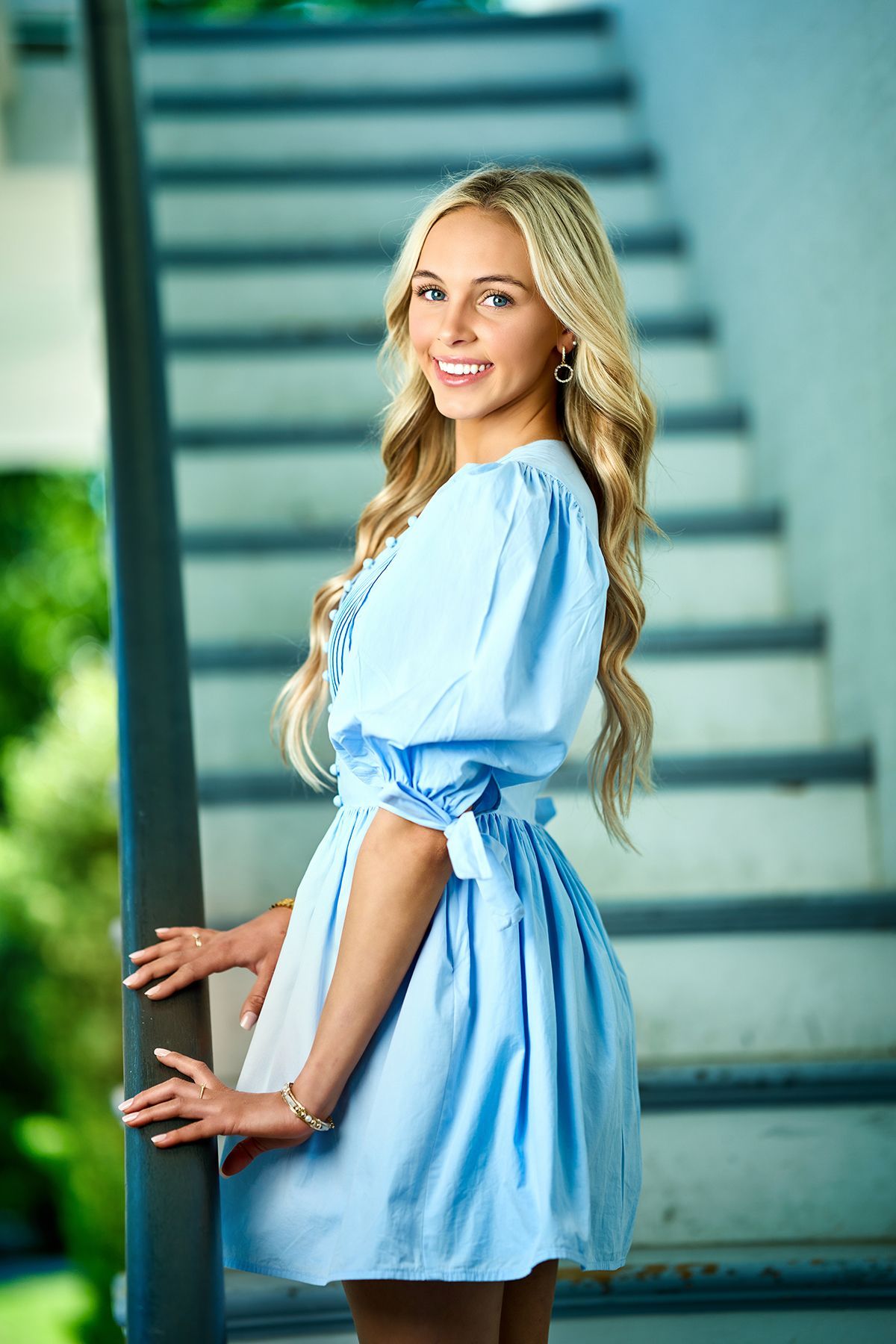 A woman wearing a cowboy hat and boots is sitting next to a wagon wheel.