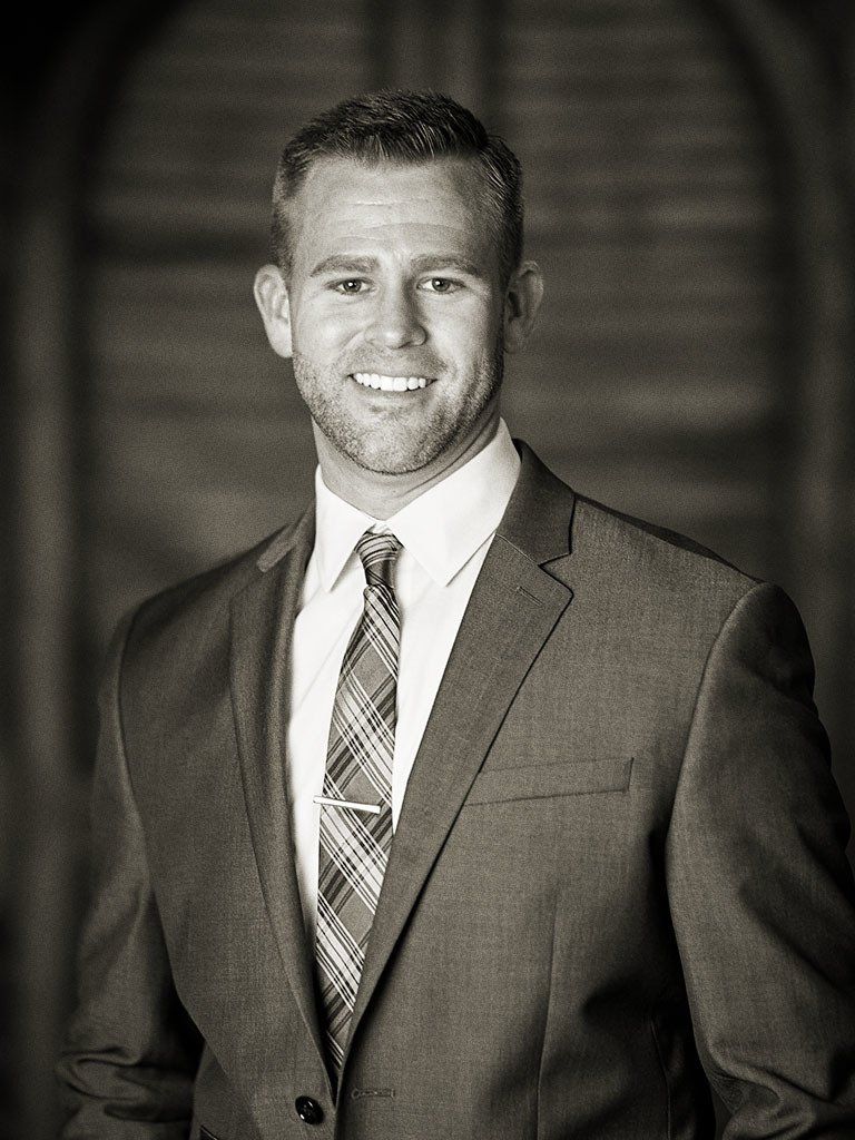 A man in a suit and tie is smiling in a black and white photo.