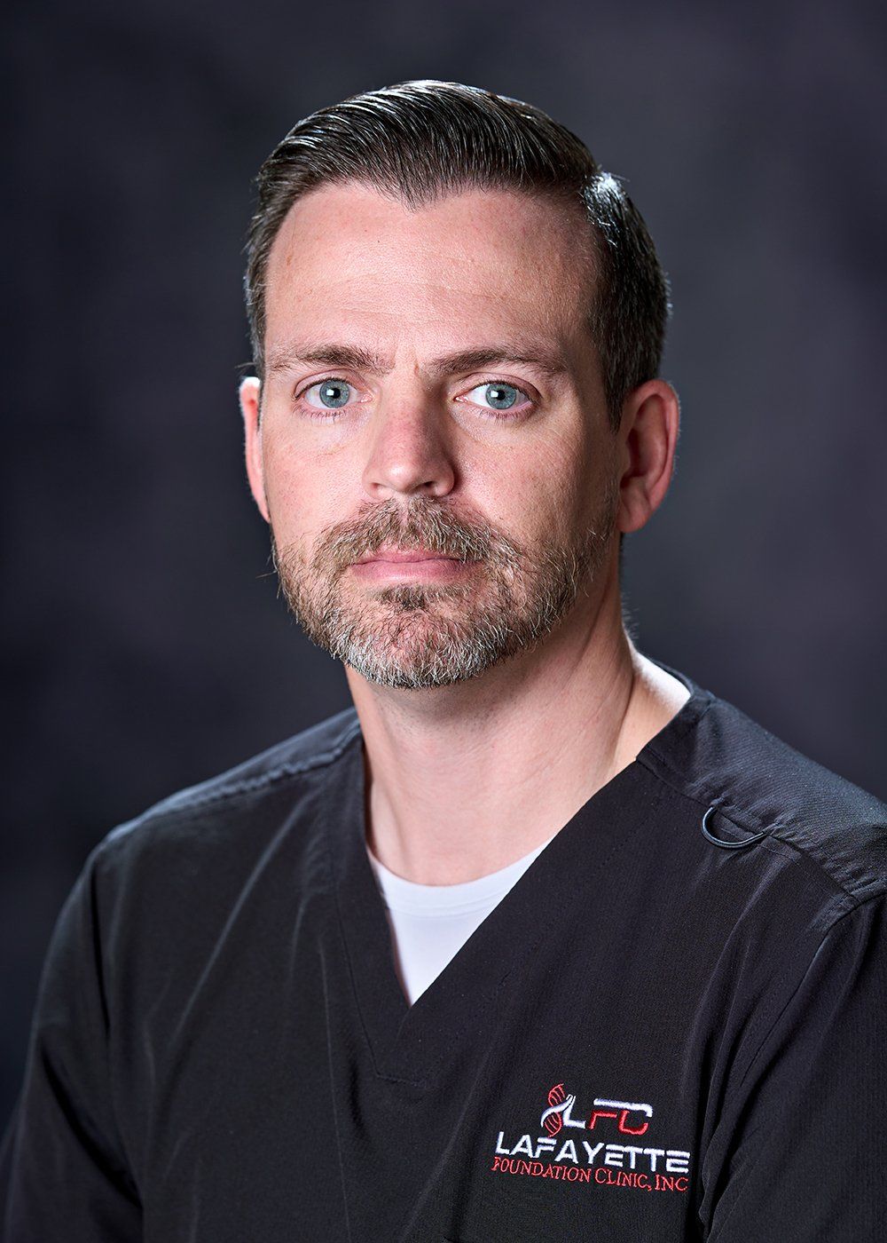 A man with a beard is wearing a black scrub top.