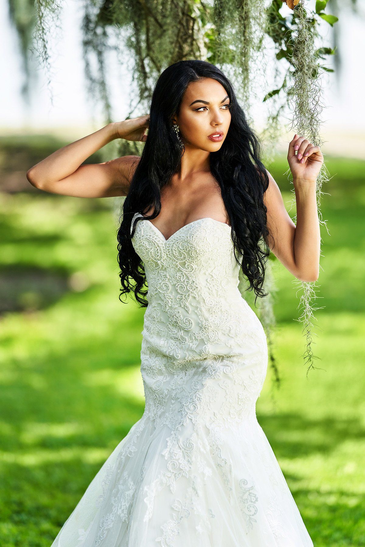 A woman in a wedding dress is standing under a tree.