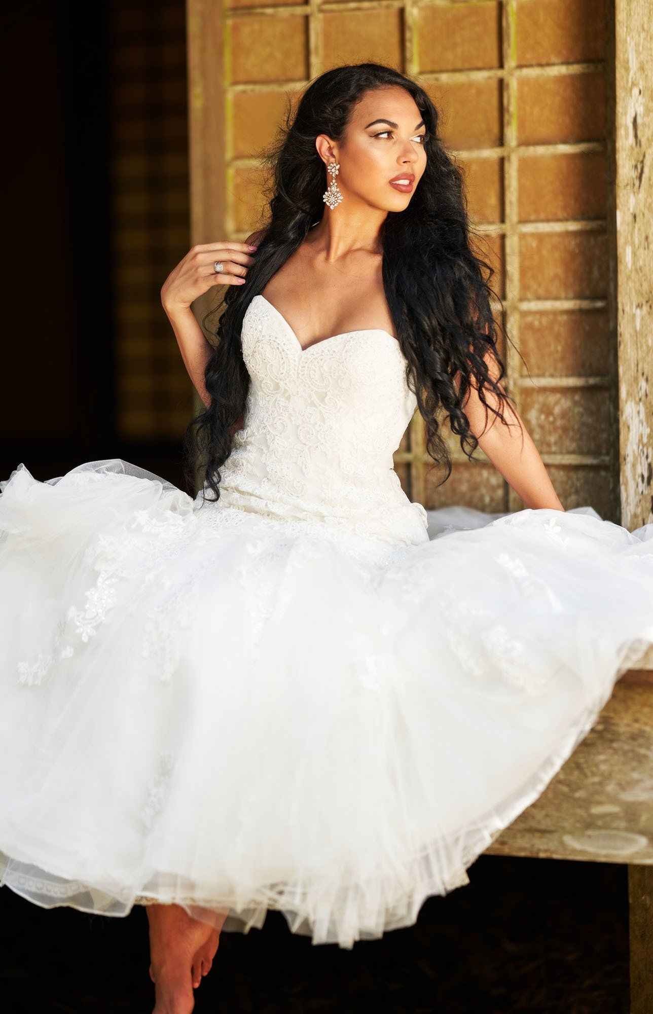 A woman in a white wedding dress is sitting on a bench.