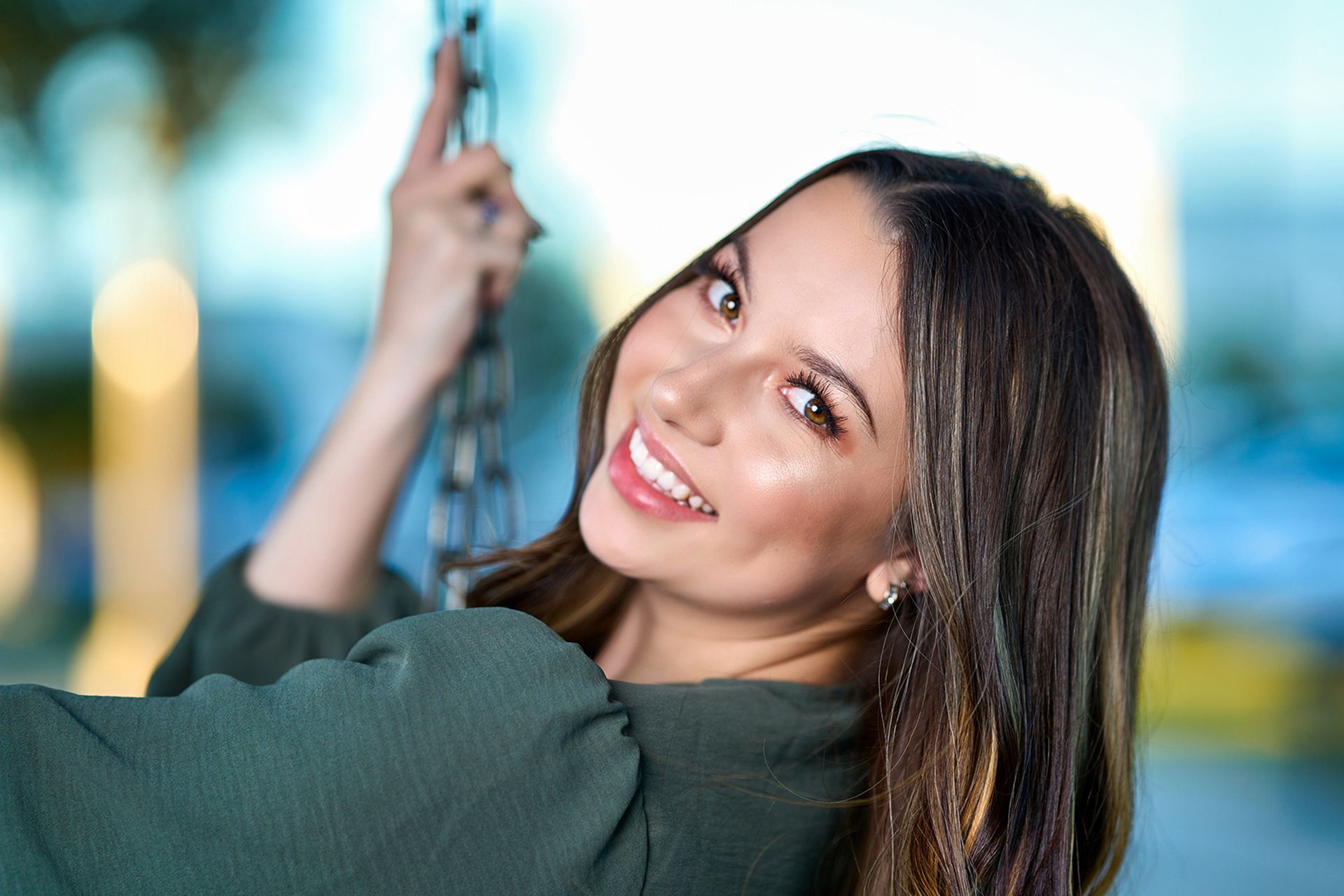 A woman is smiling while sitting on a swing.