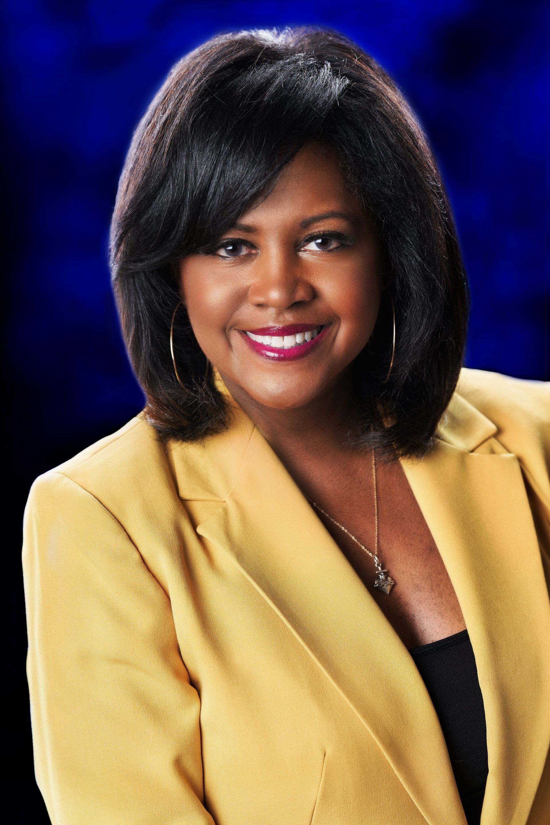 A woman in a yellow jacket is smiling for the camera