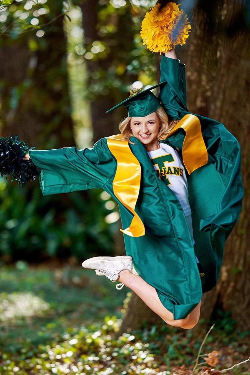 A woman in a graduation cap and gown is jumping in the air