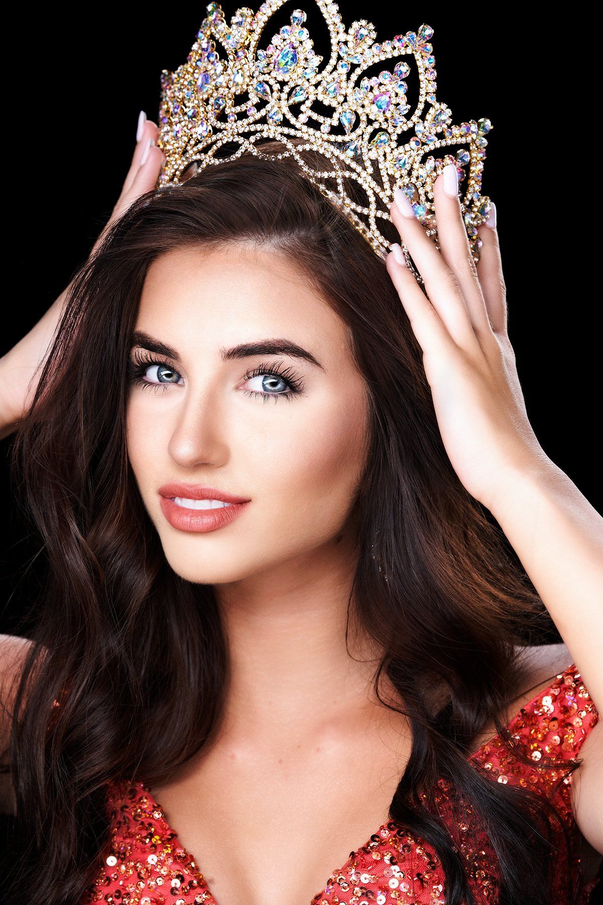 A woman in a red dress is wearing a crown on her head