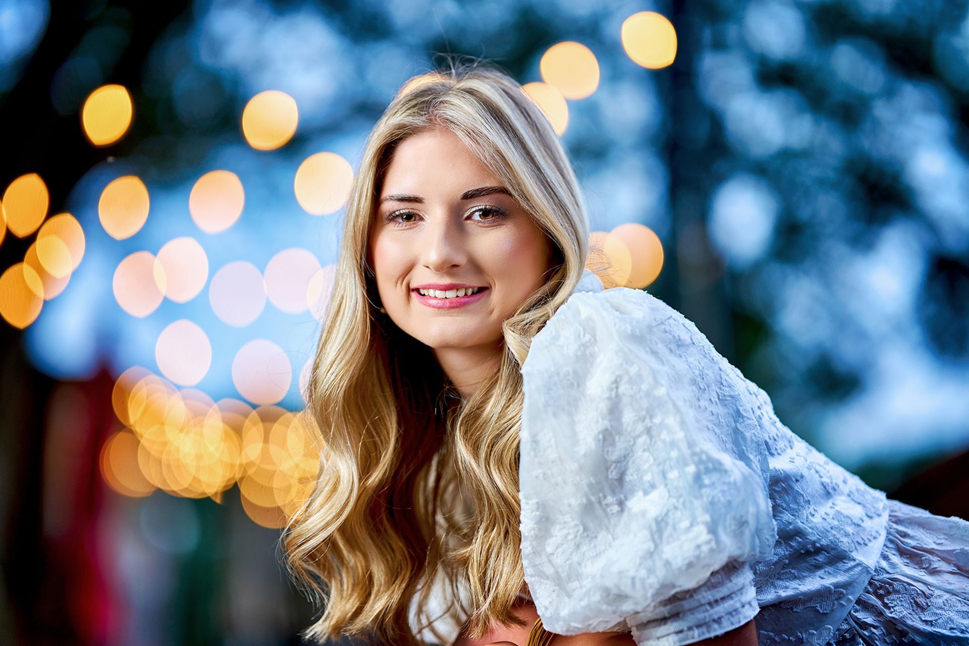 A young woman is posing for a picture in front of a blurry background.