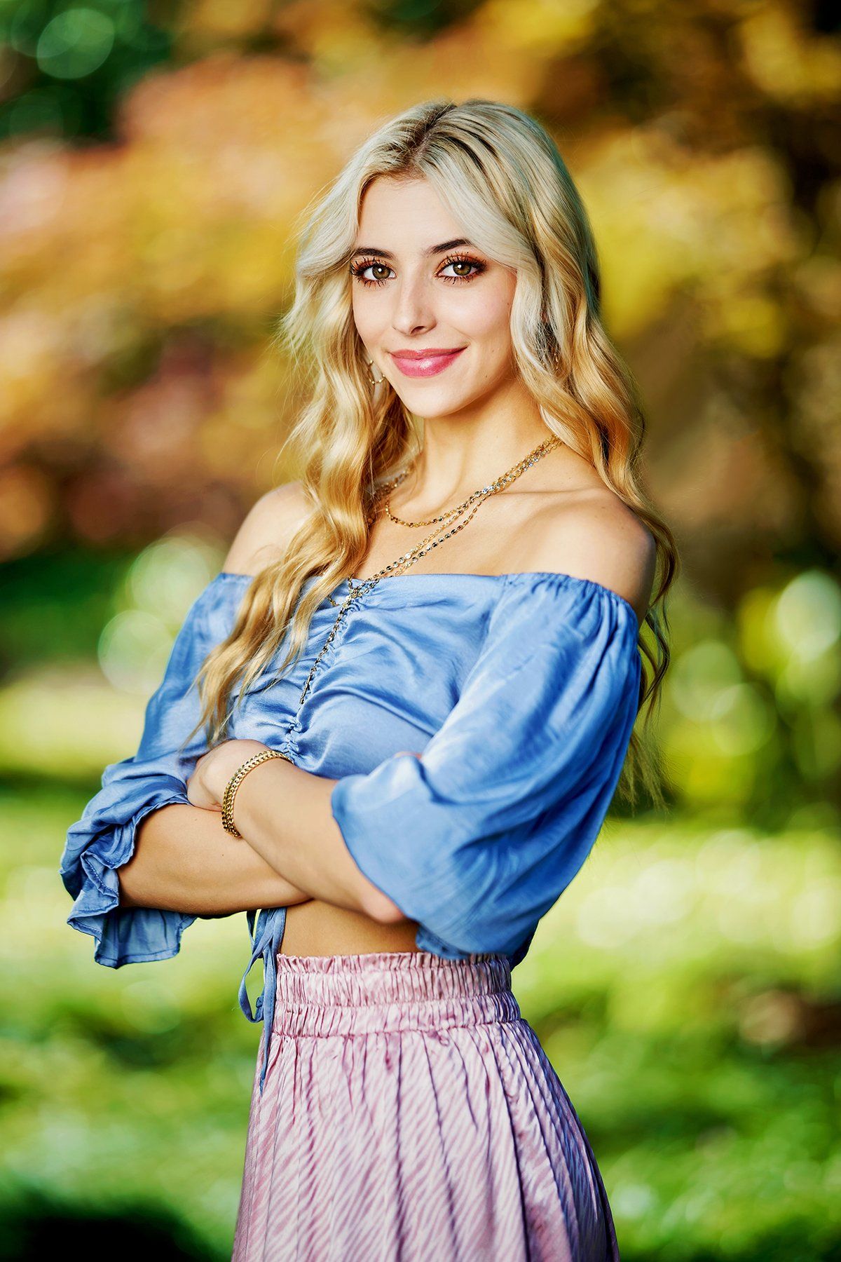 The woman is wearing a blue off the shoulder top and a pink skirt.