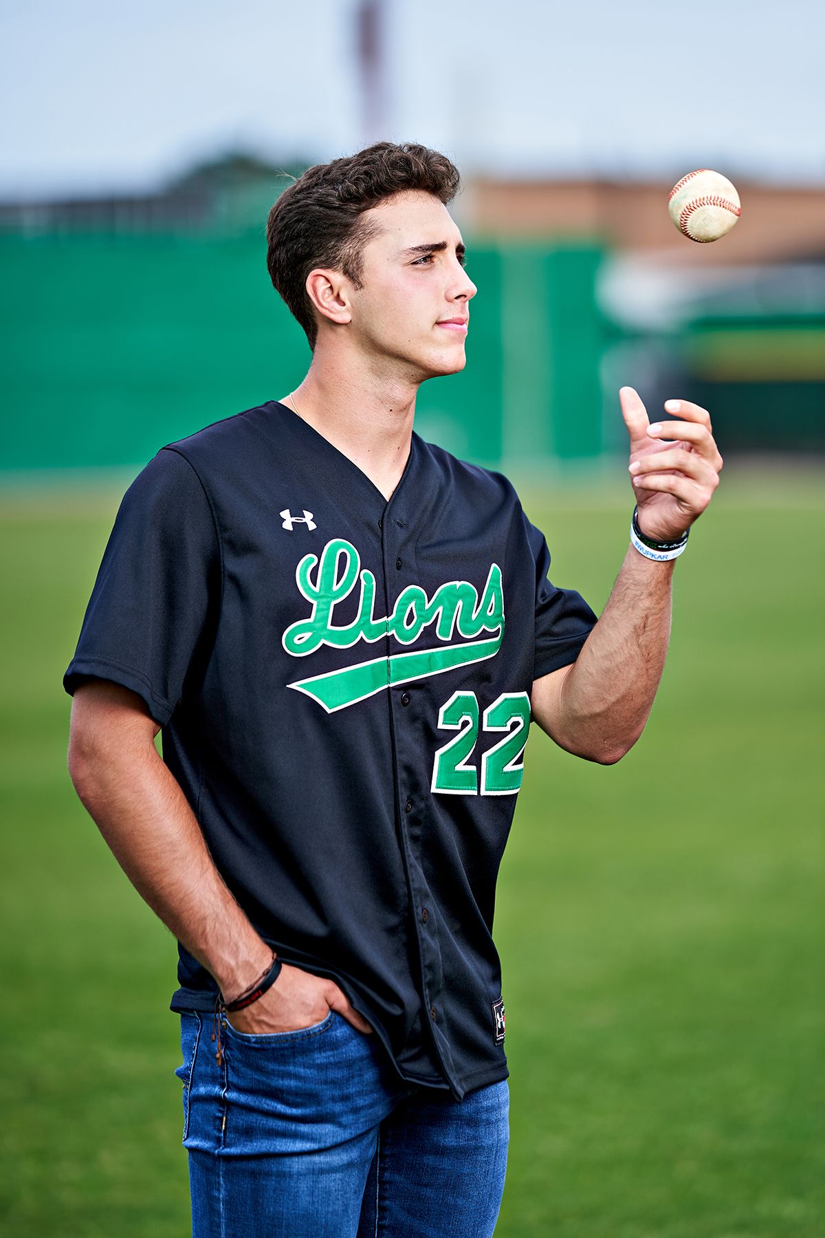 A young man in a baseball uniform is throwing a baseball.