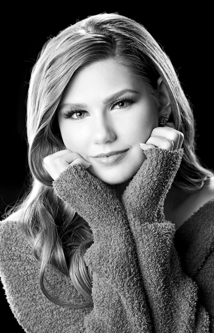 A black and white photo of a woman wearing a sweater.