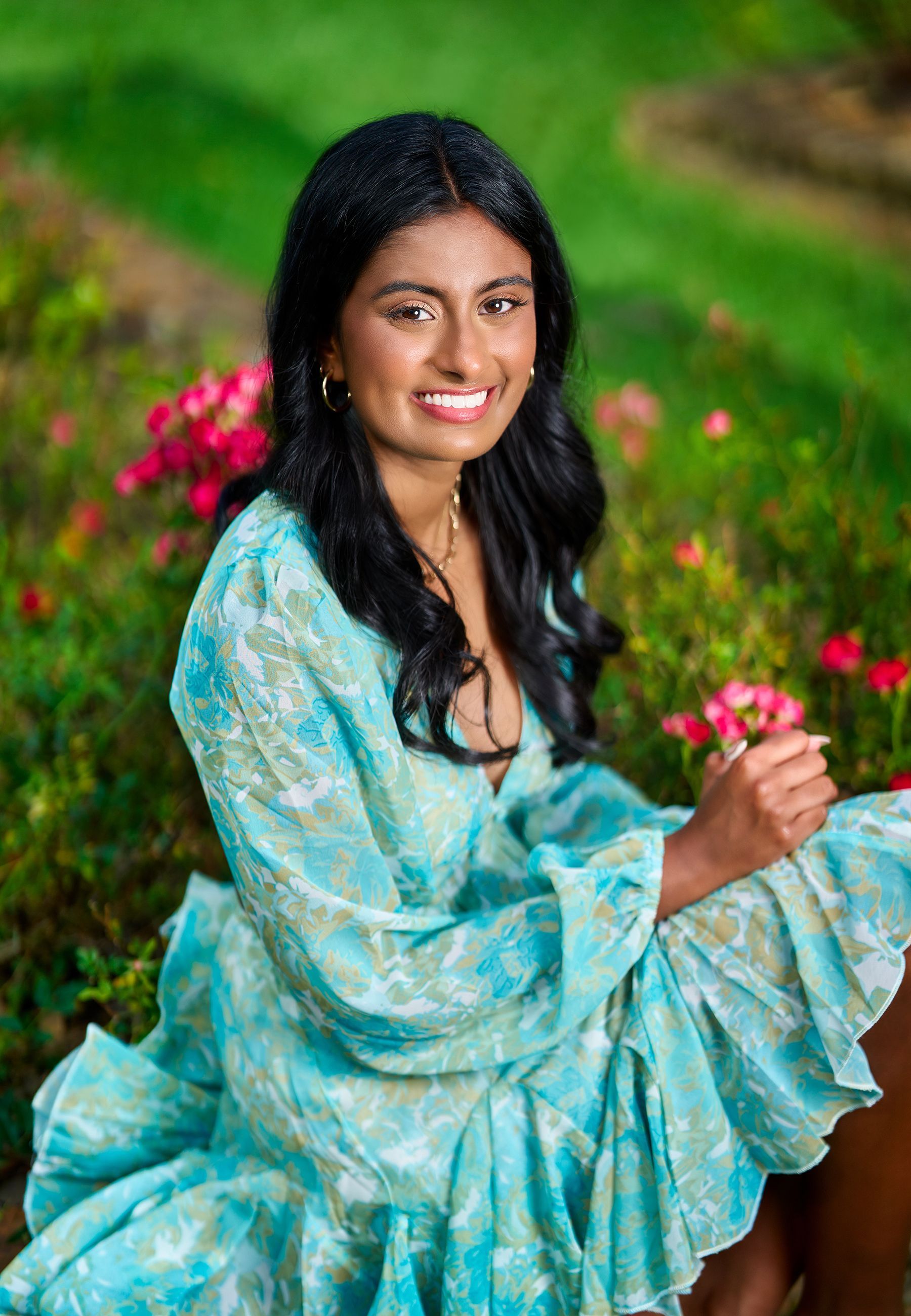 A woman in a blue dress is sitting in a field of flowers.