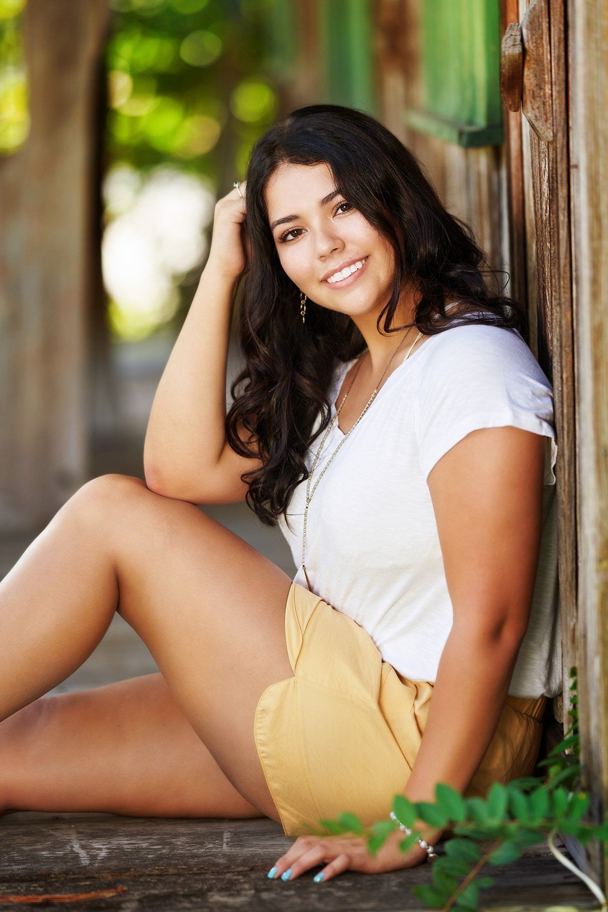 A young woman is sitting on the ground leaning against a wall.