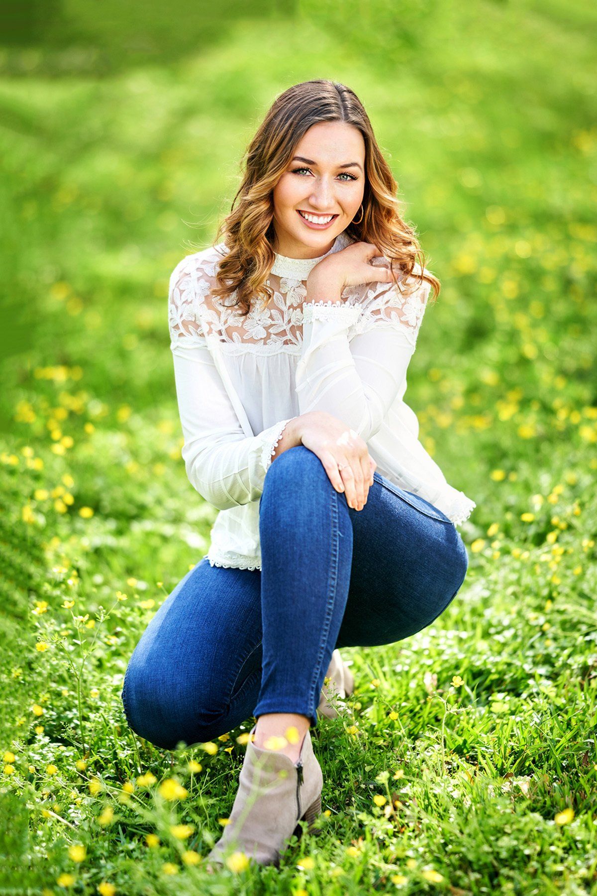 A young woman is squatting down in a field of flowers.