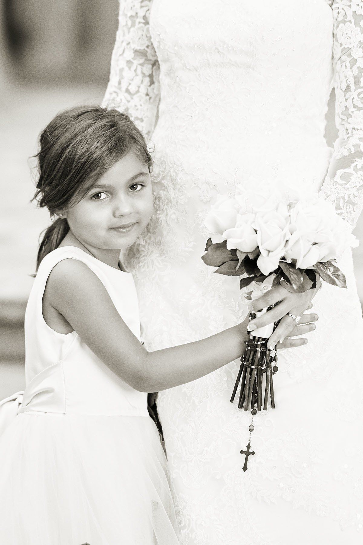 A little girl is holding a bouquet of flowers next to a bride in a wedding dress.