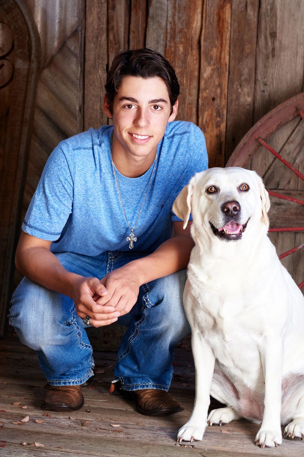 A young man is kneeling next to a white dog