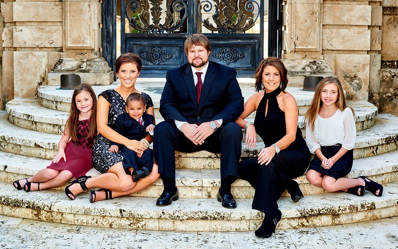 A family is posing for a picture on the steps of a building.