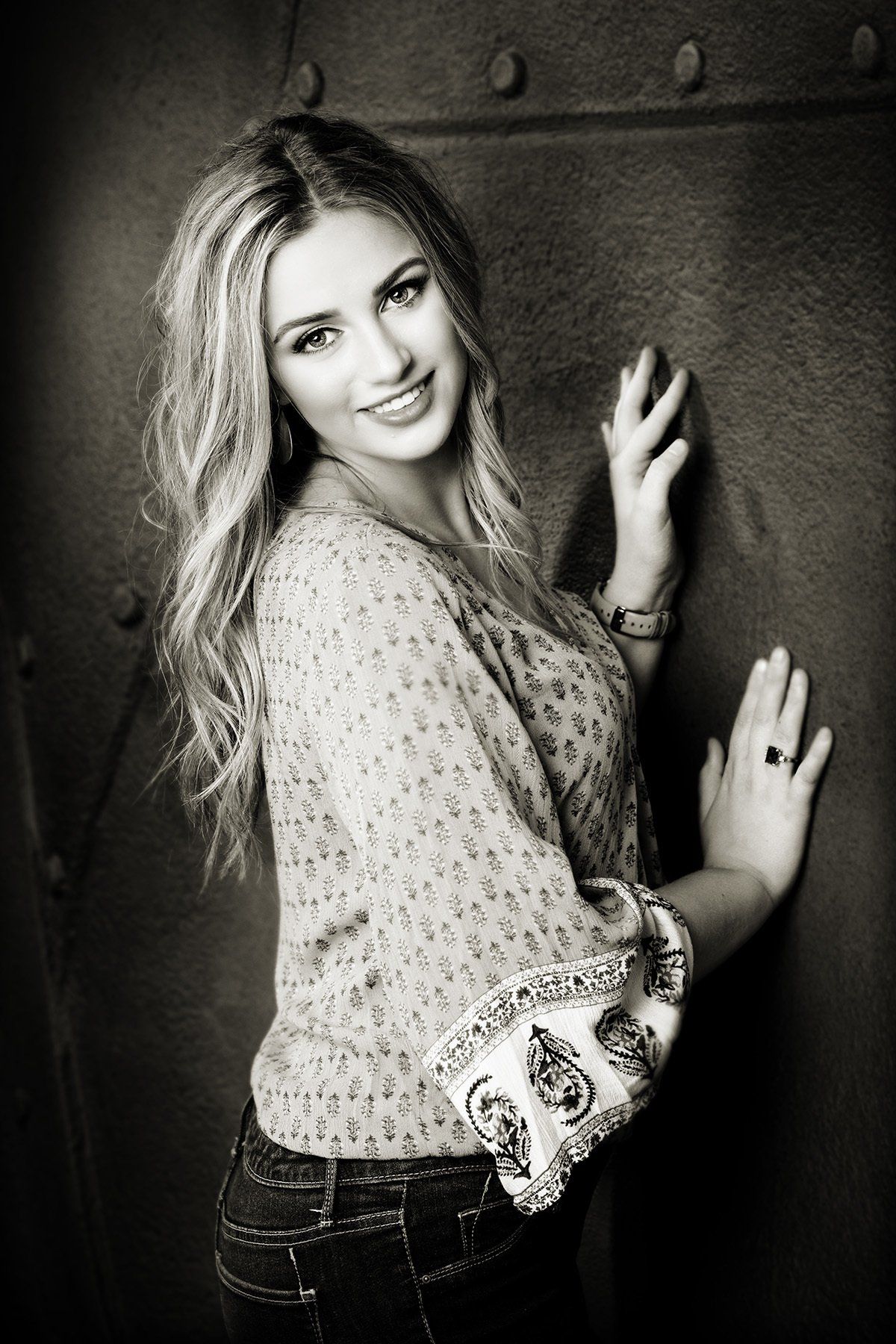 A black and white photo of a woman leaning against a wall.