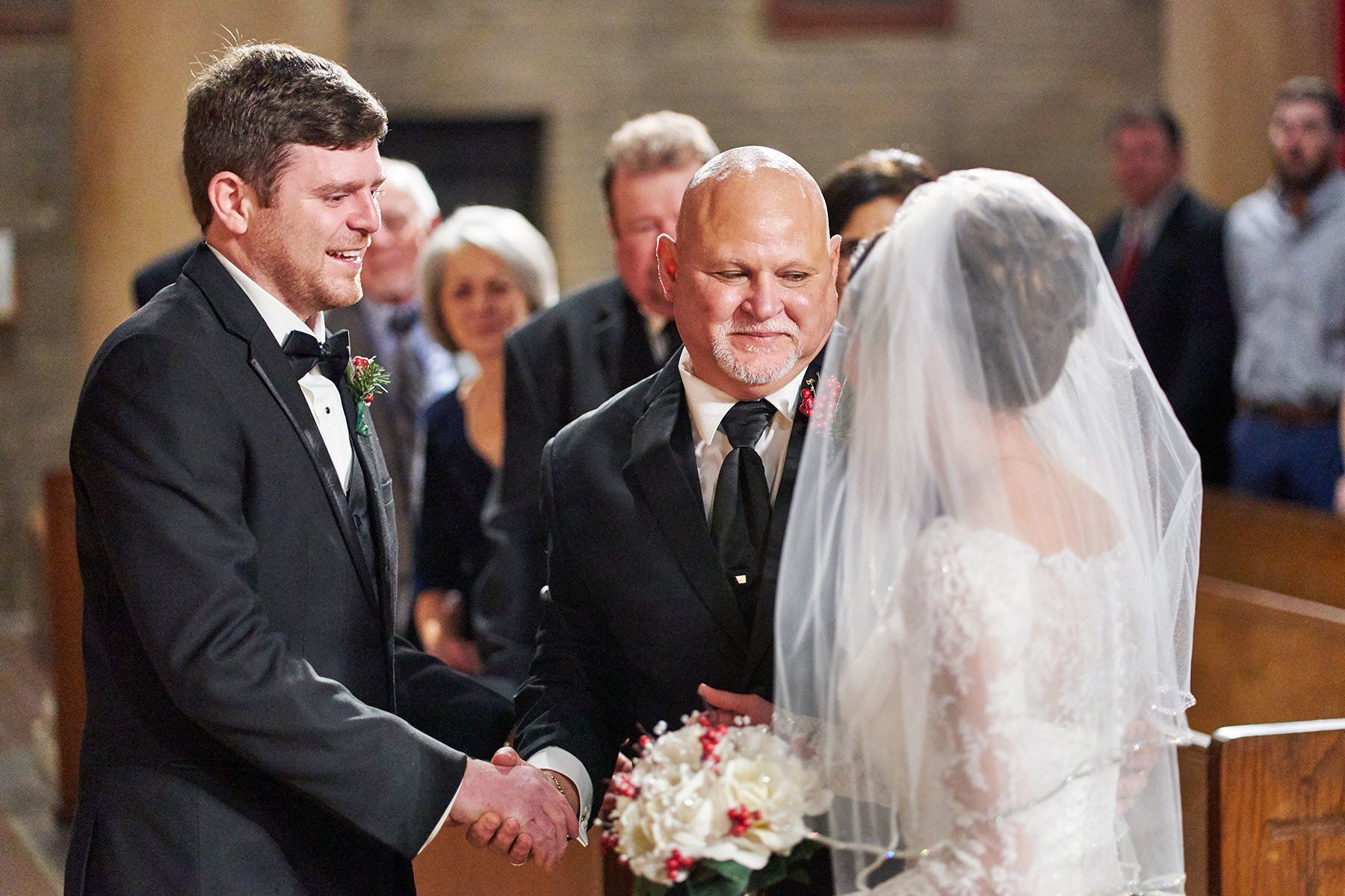 A bride and groom are shaking hands in a church.