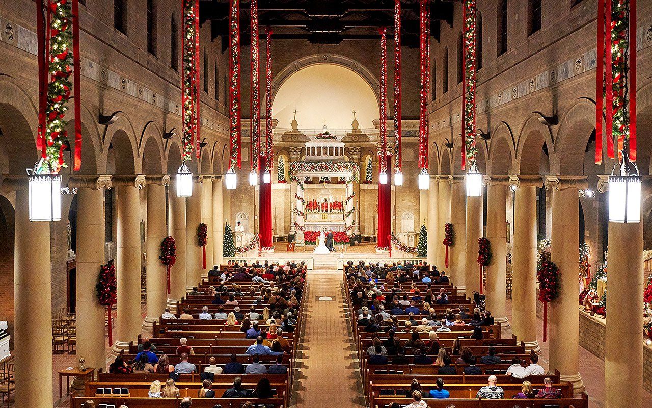 A large church filled with people is decorated for christmas.