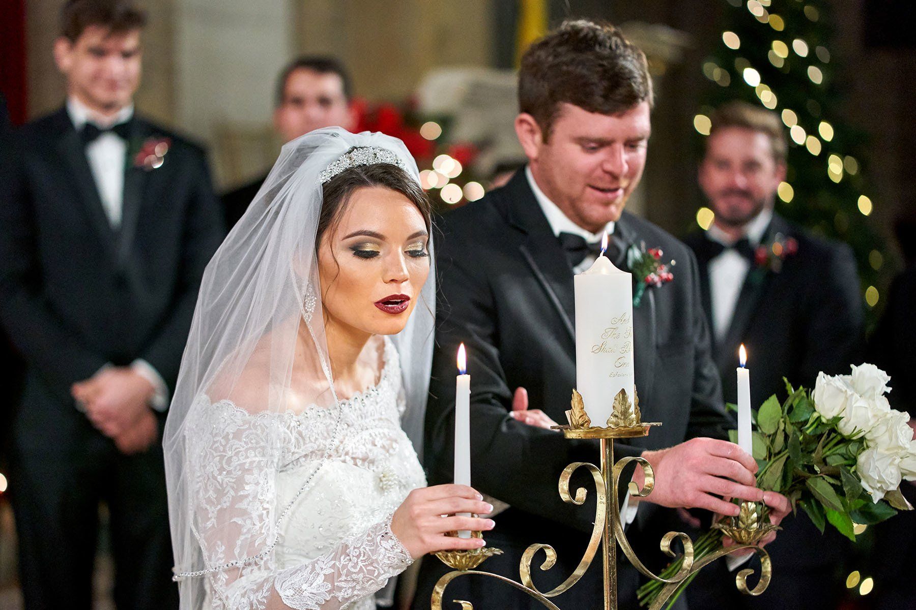 A bride and groom are lighting candles at their wedding ceremony.
