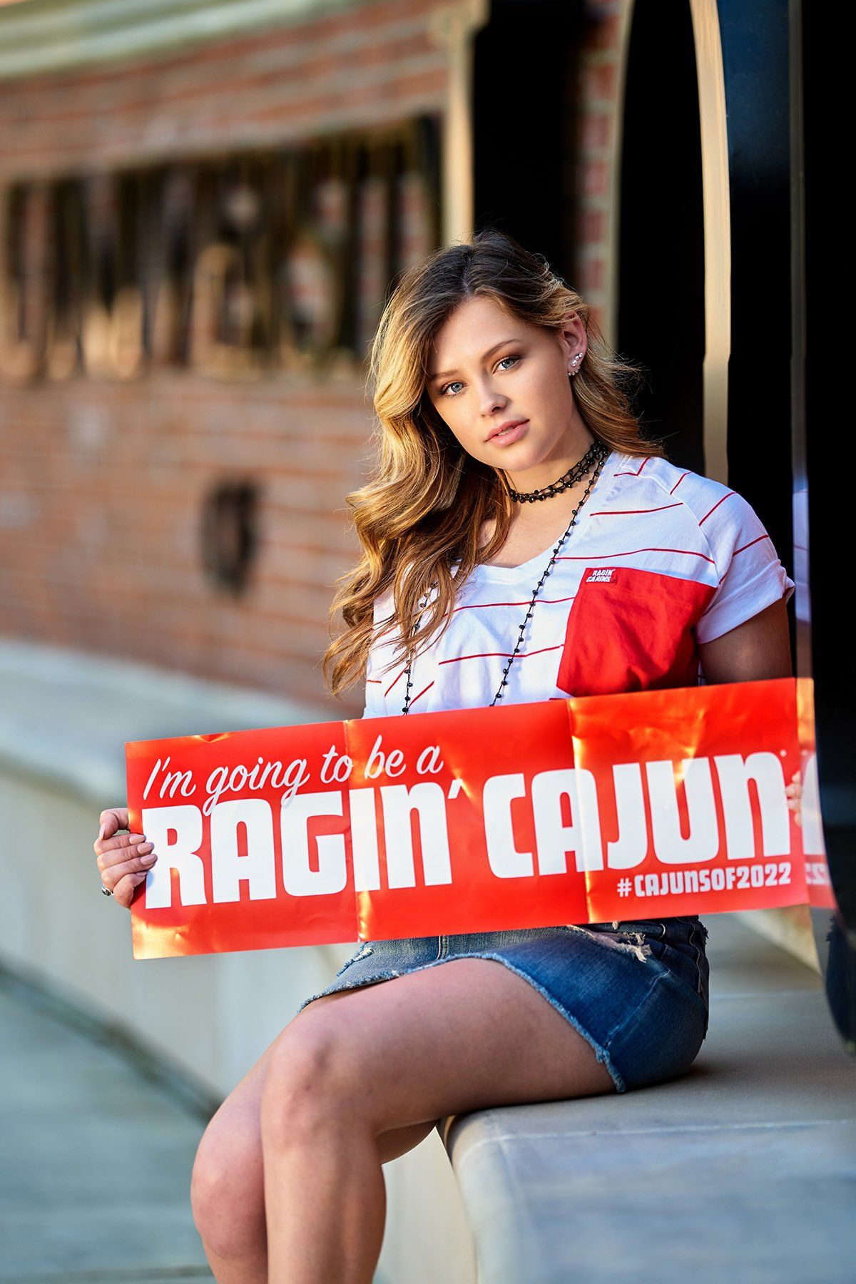 A woman is holding a sign that says `` i 'm going to be a ragin ' cajun ''
