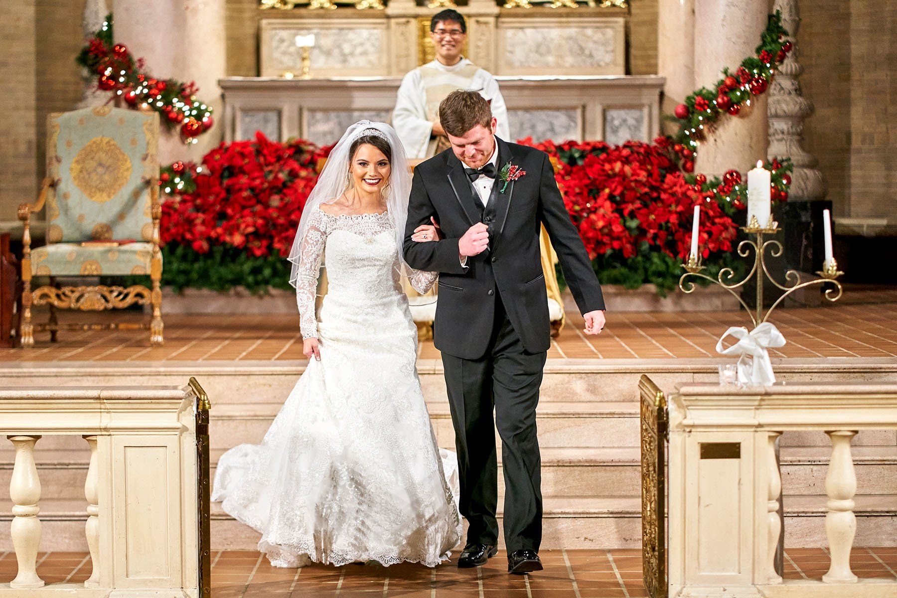 A bride and groom are walking down the aisle of a church.