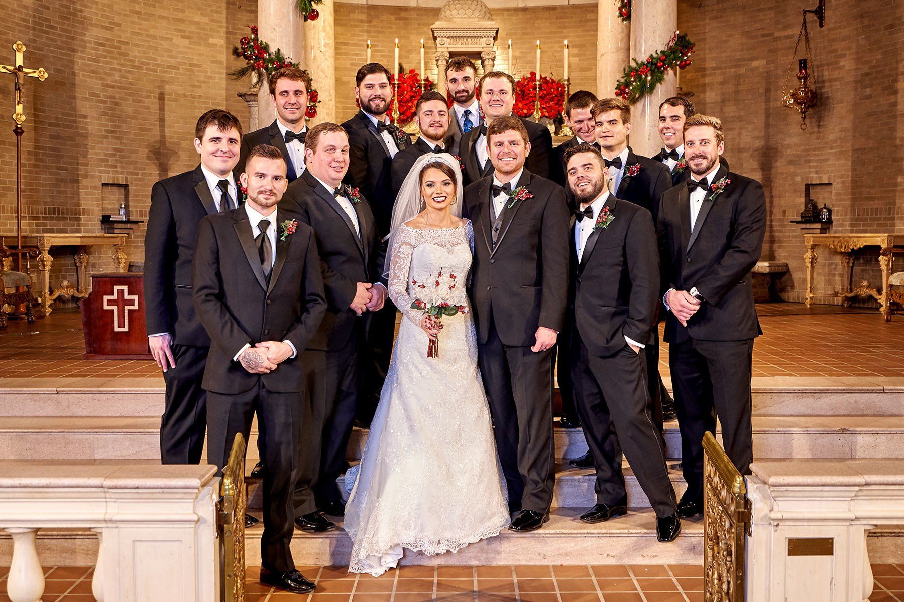 A bride and groom are posing for a picture with their wedding party in a church.