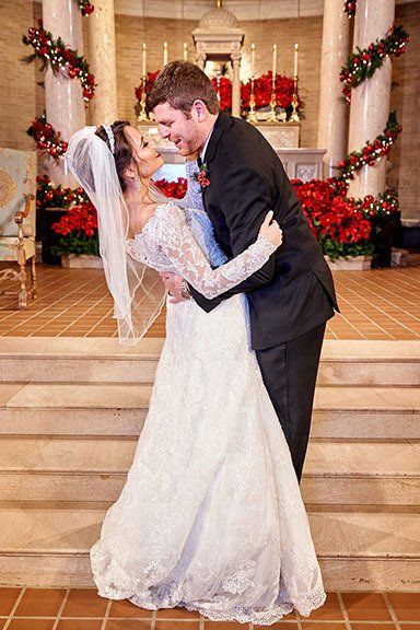 A bride and groom are kissing in front of a church.