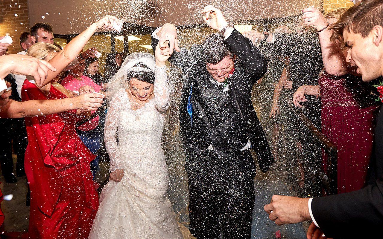 A bride and groom are being showered with confetti at their wedding reception.