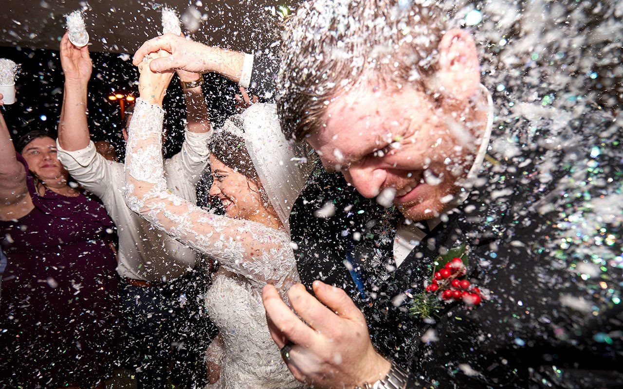 A bride and groom are being showered with confetti at their wedding reception.