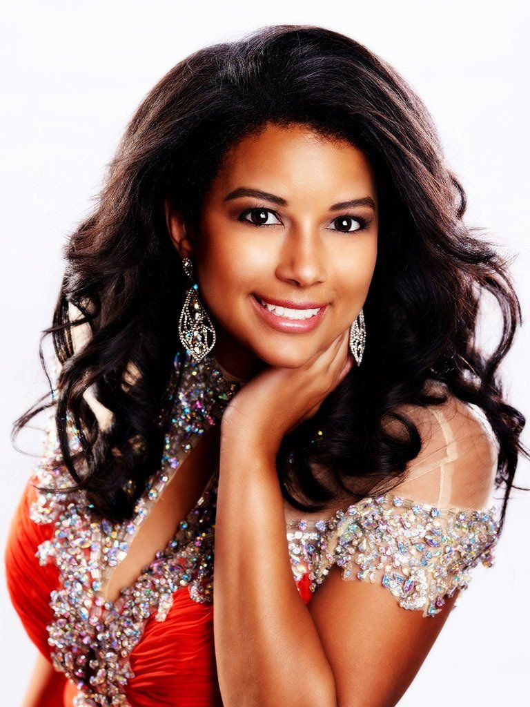 A woman in a red dress is smiling with her hand on her chin