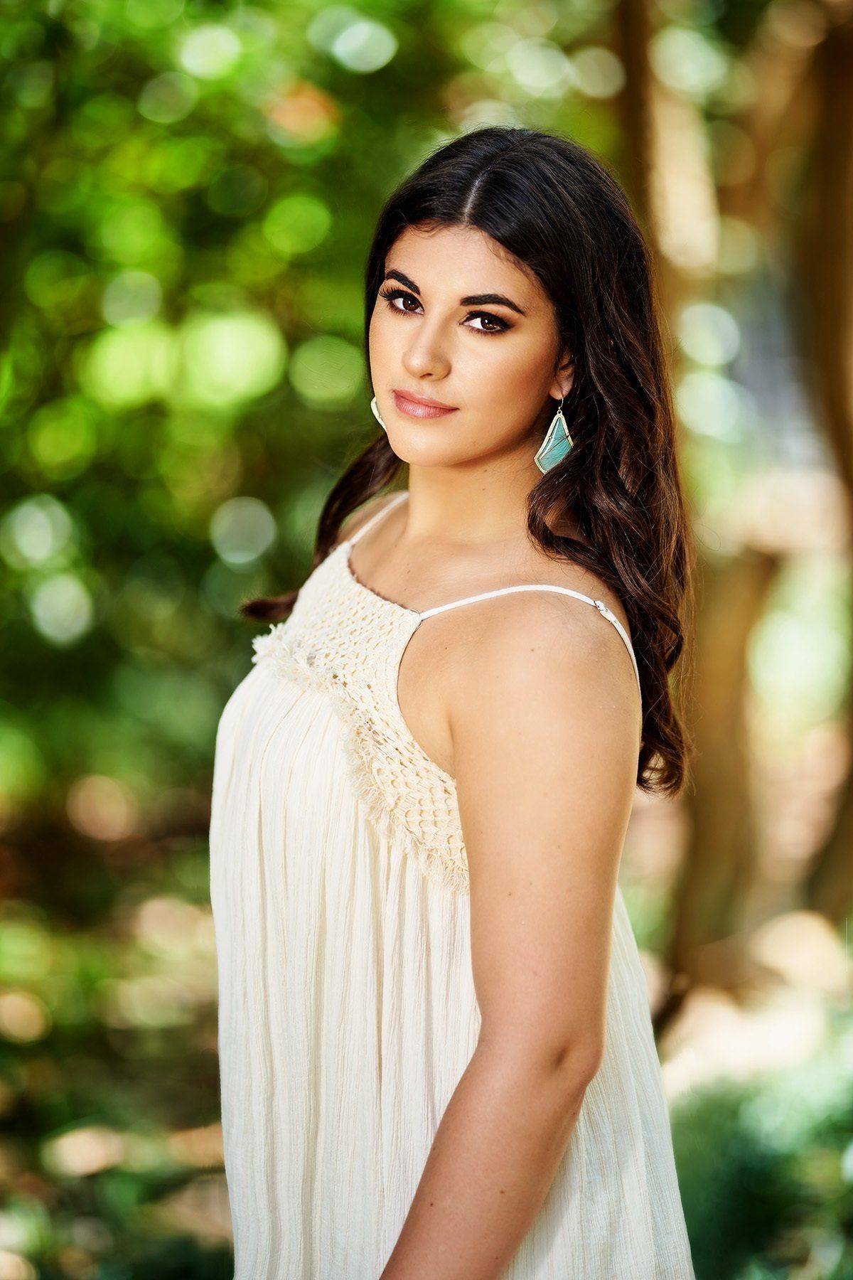 A woman in a white dress is standing in the woods.