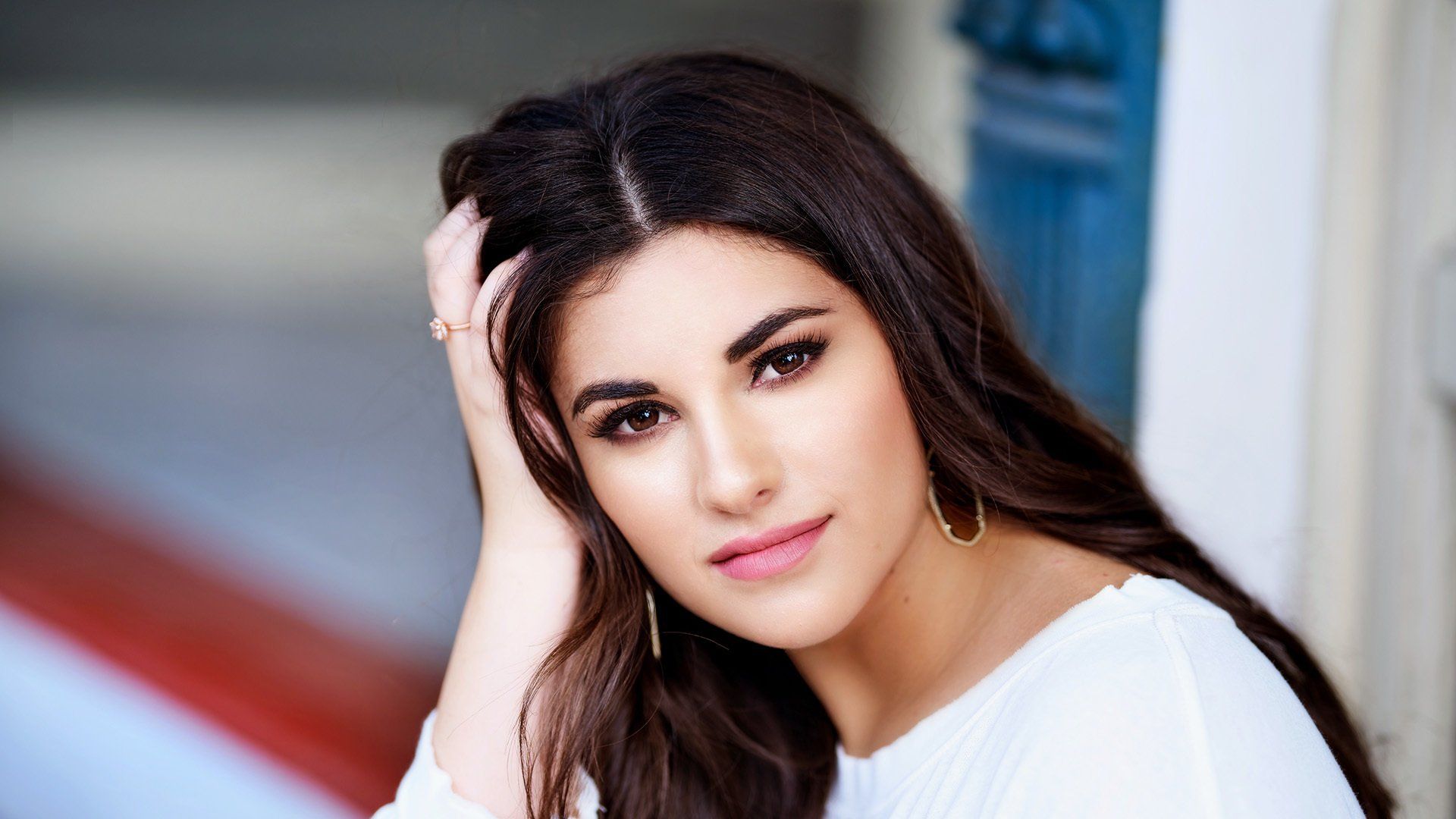A close up of a woman 's face with her hand on her hair.