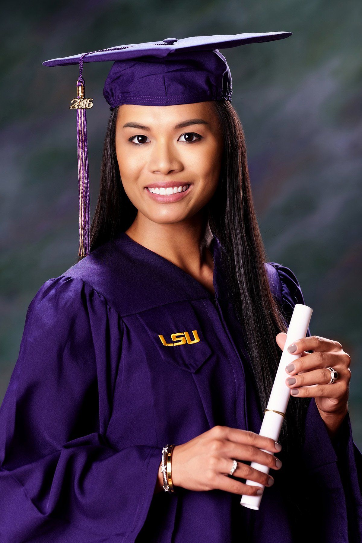 A woman in a purple graduation cap and gown is holding a diploma