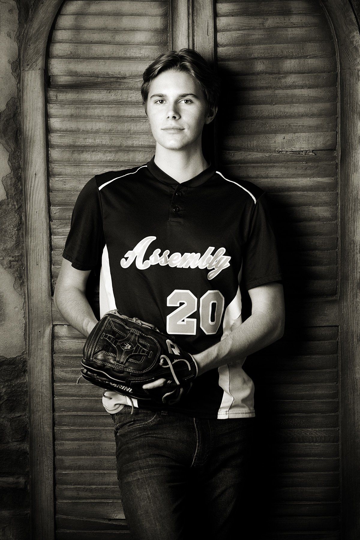 A young man in a baseball uniform is holding a baseball glove.