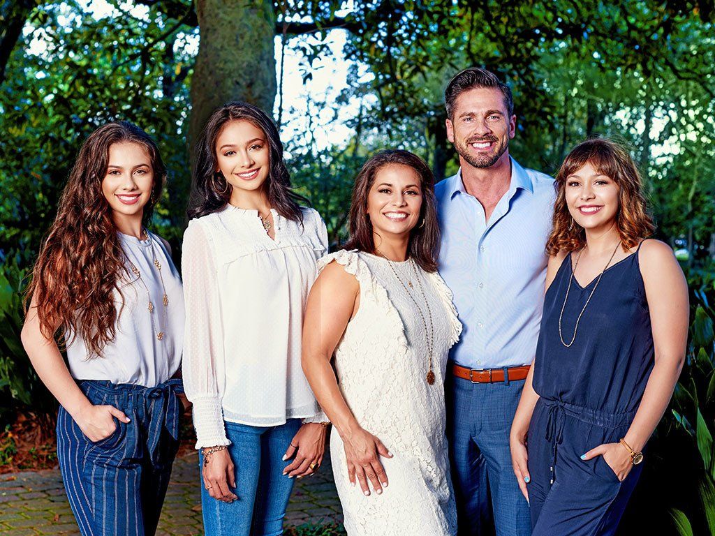 A family is posing for a picture together in a park.