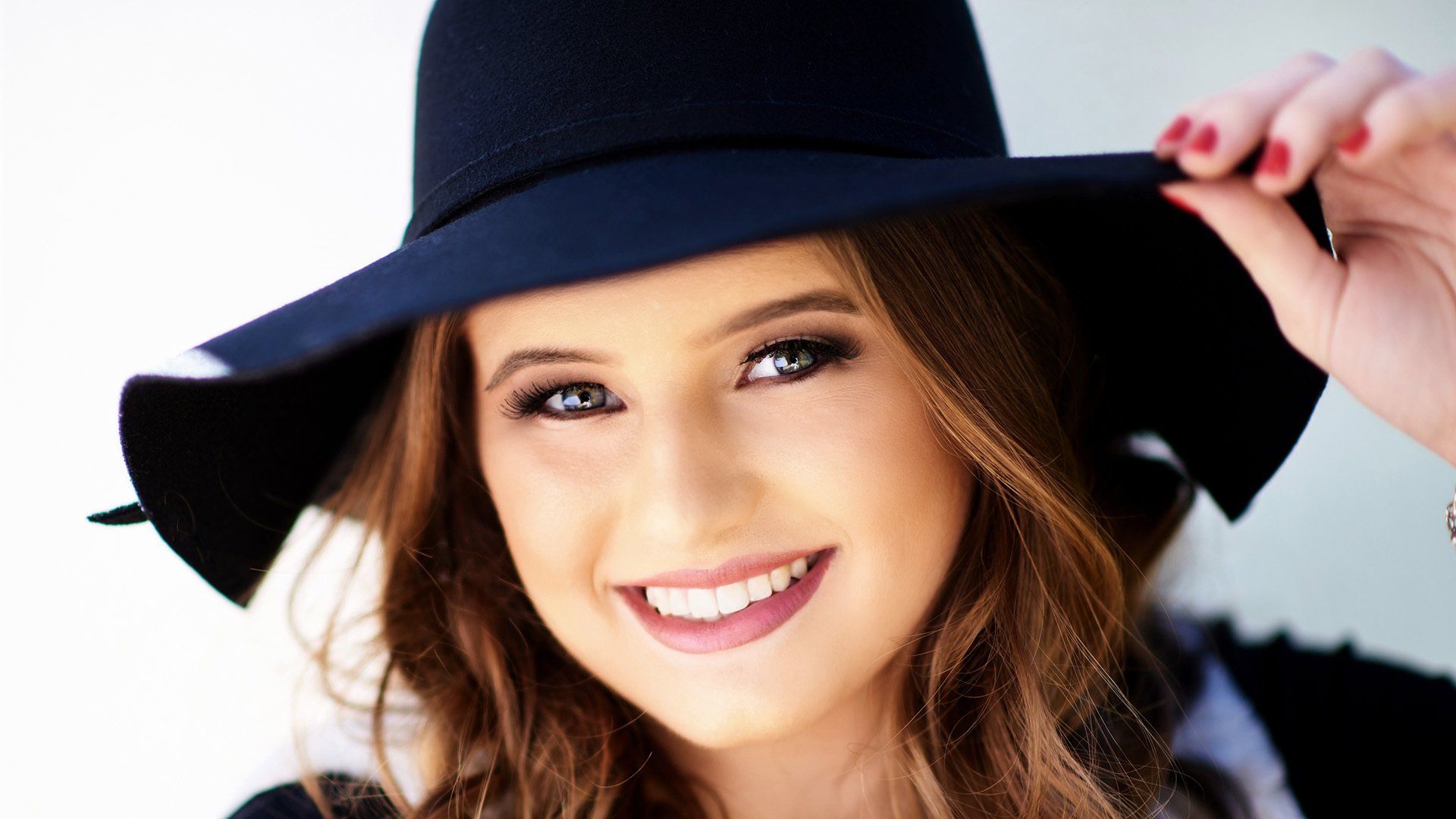 A woman is wearing a black hat and smiling.