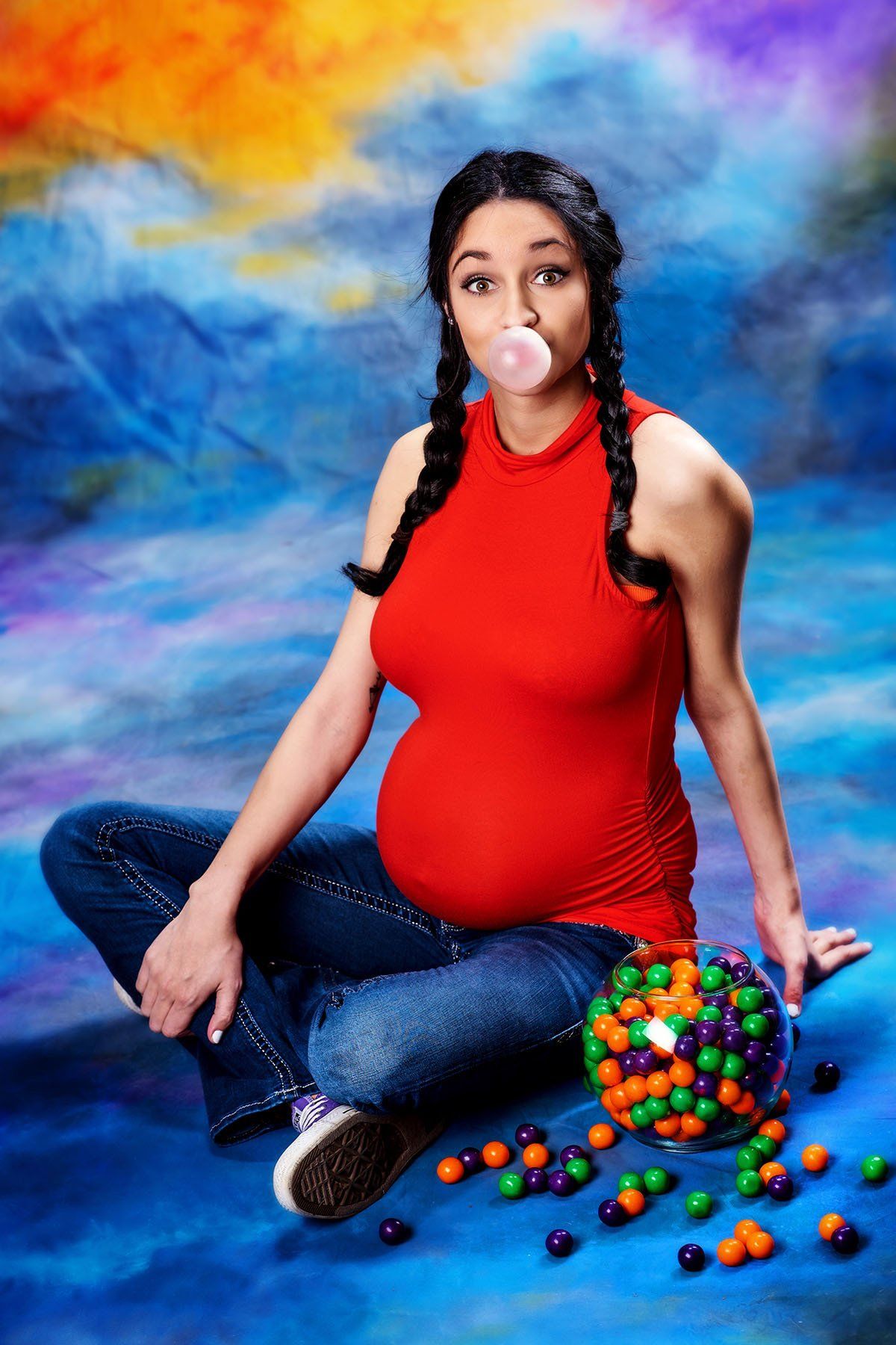 A pregnant woman blowing a bubble with a bowl of gum
