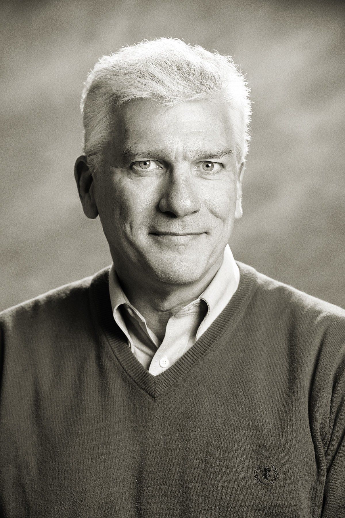 A black and white photo of a man wearing a sweater and a shirt.