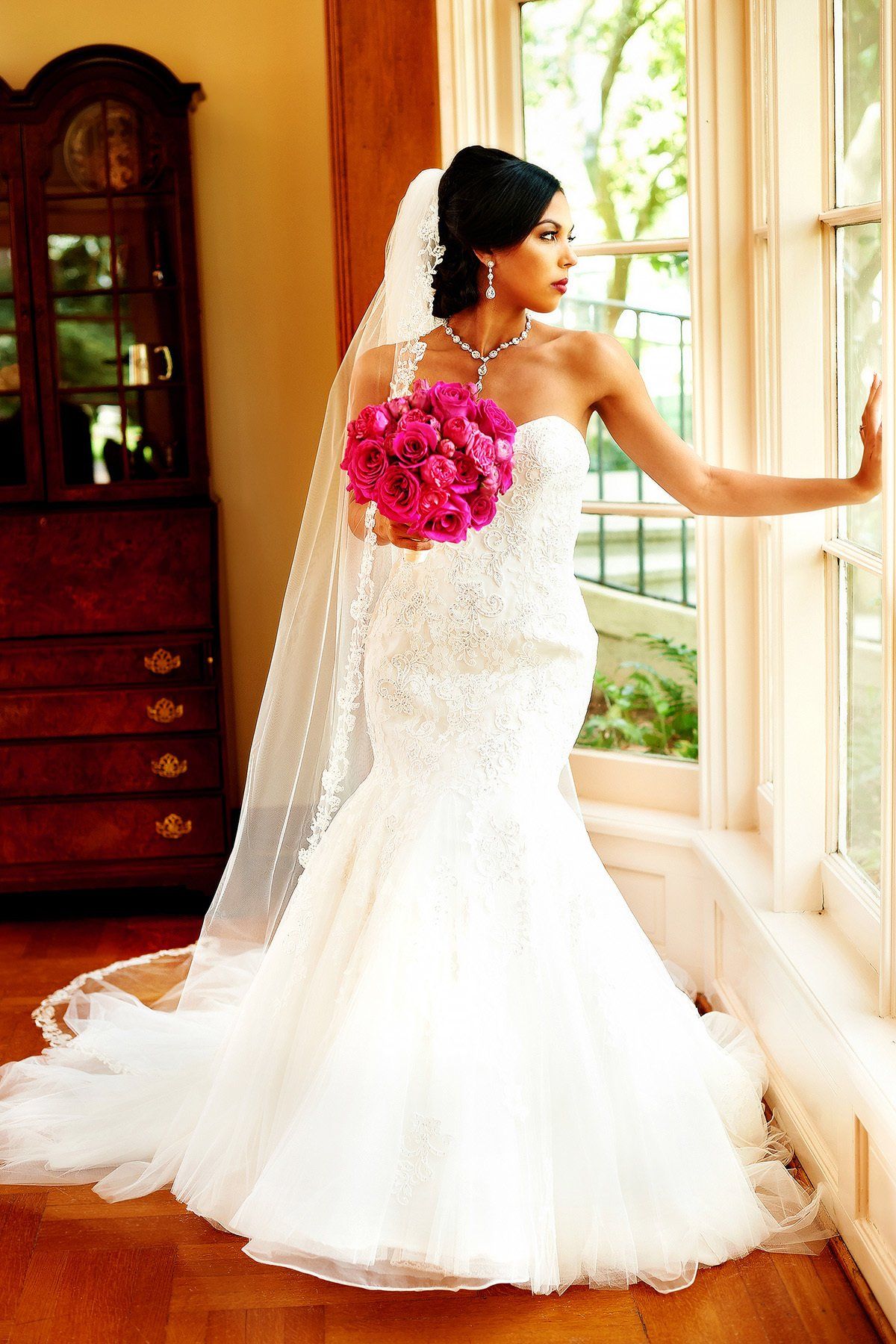 A woman in a wedding dress holds a bouquet of pink flowers