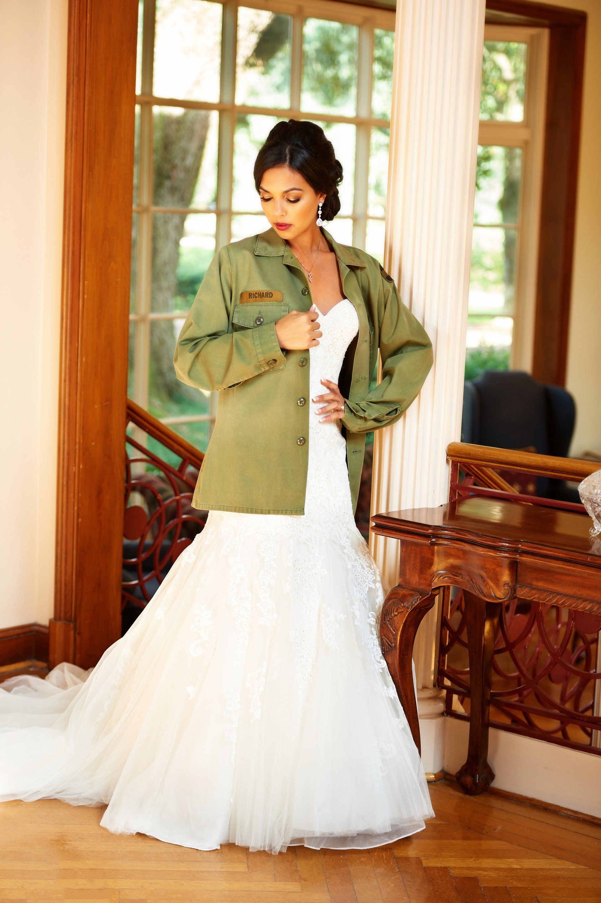 A woman in a wedding dress is wearing a military jacket