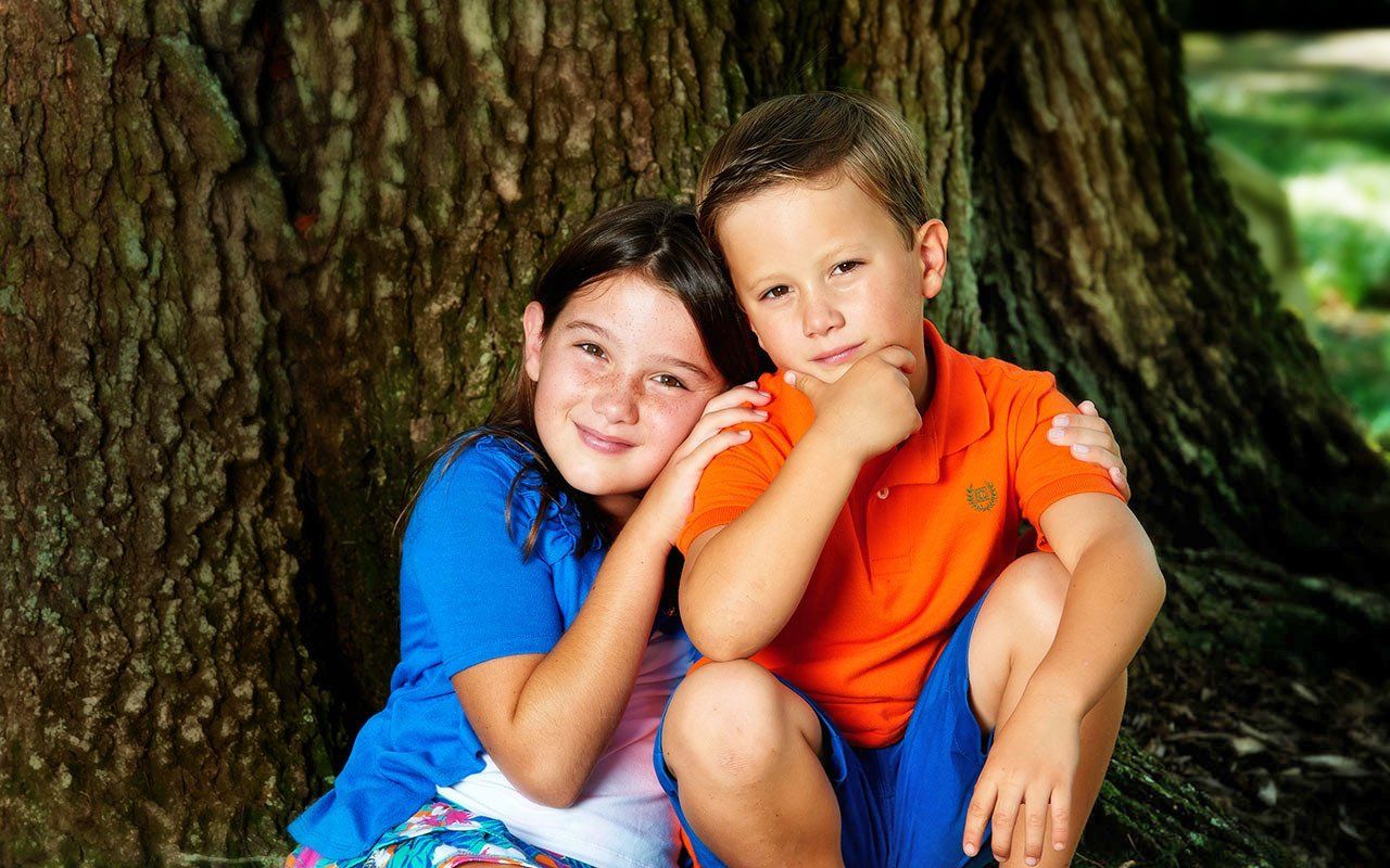 A boy and a girl are sitting under a tree.