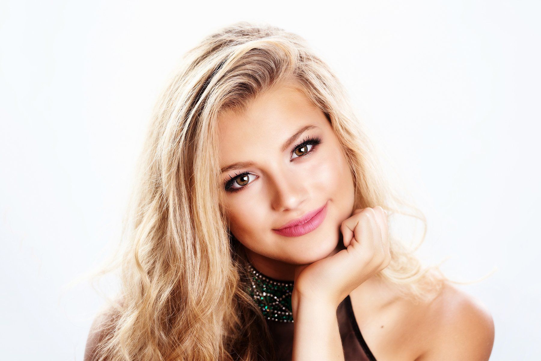 A close up of a woman 's face with her hand on her chin.