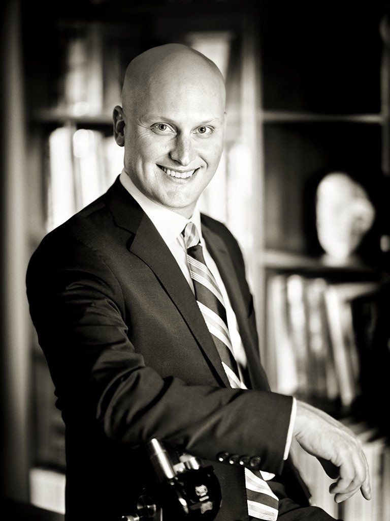 A man in a suit and tie is smiling in a black and white photo.