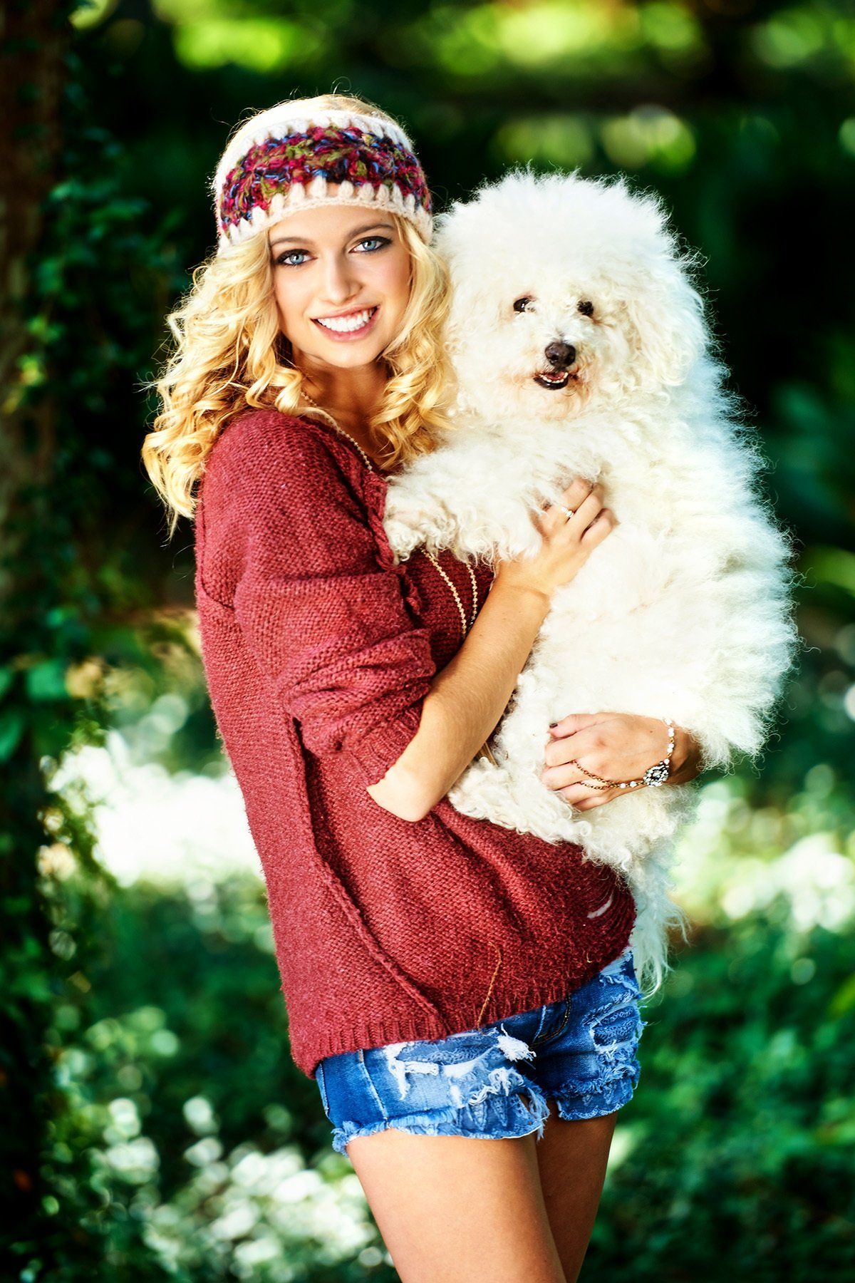 A woman is holding a small white dog in her arms.