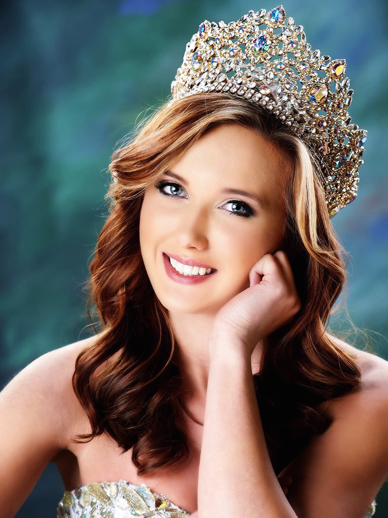 A woman wearing a tiara is smiling for the camera