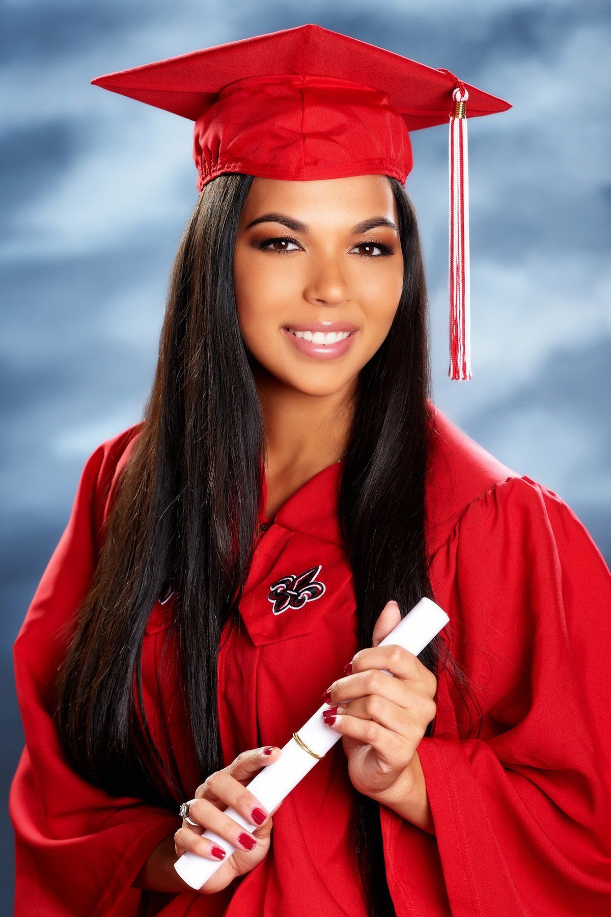 A woman in a red cap and gown is holding a diploma