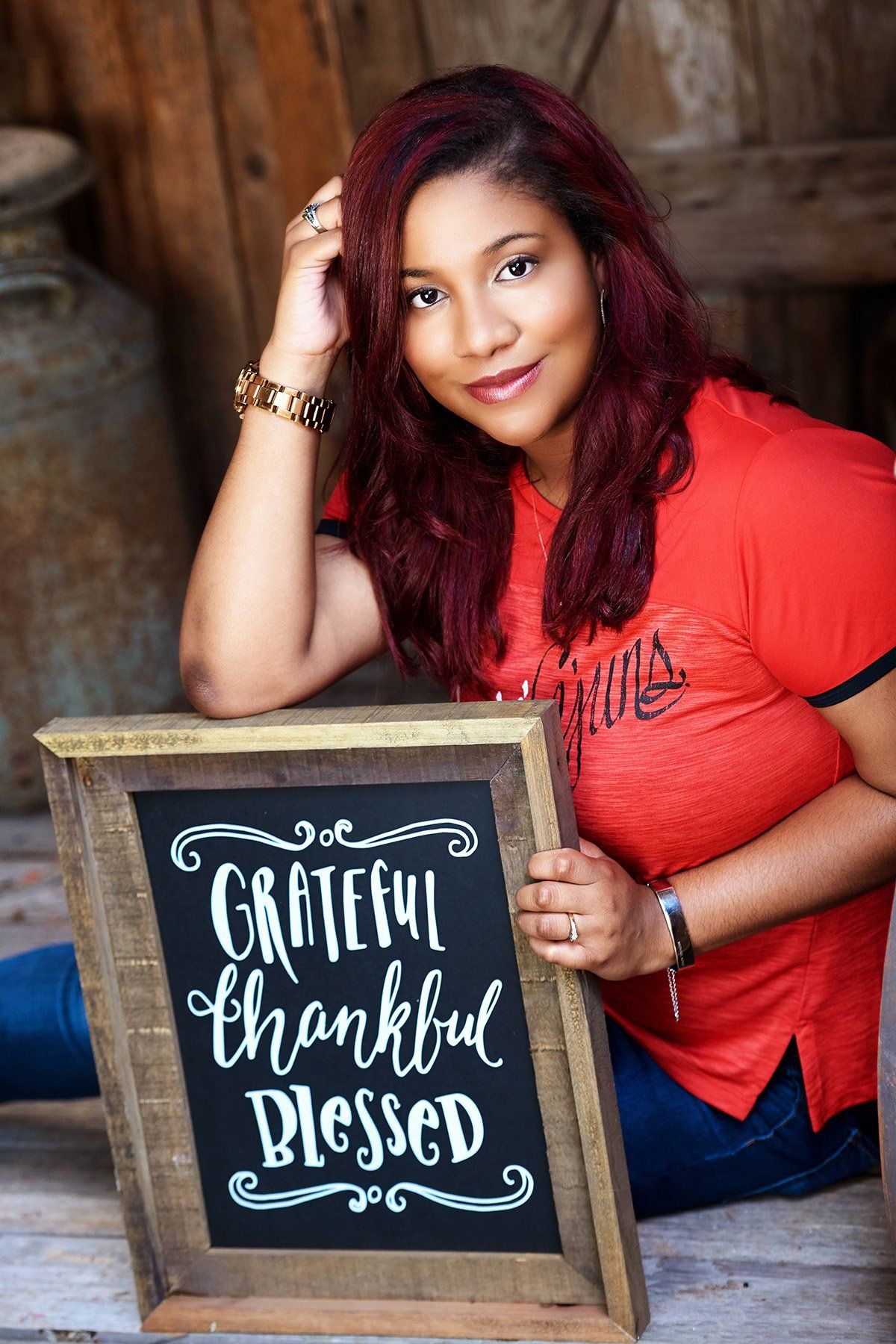 A woman is sitting on the floor holding a sign that says `` grateful thankful blessed ''.