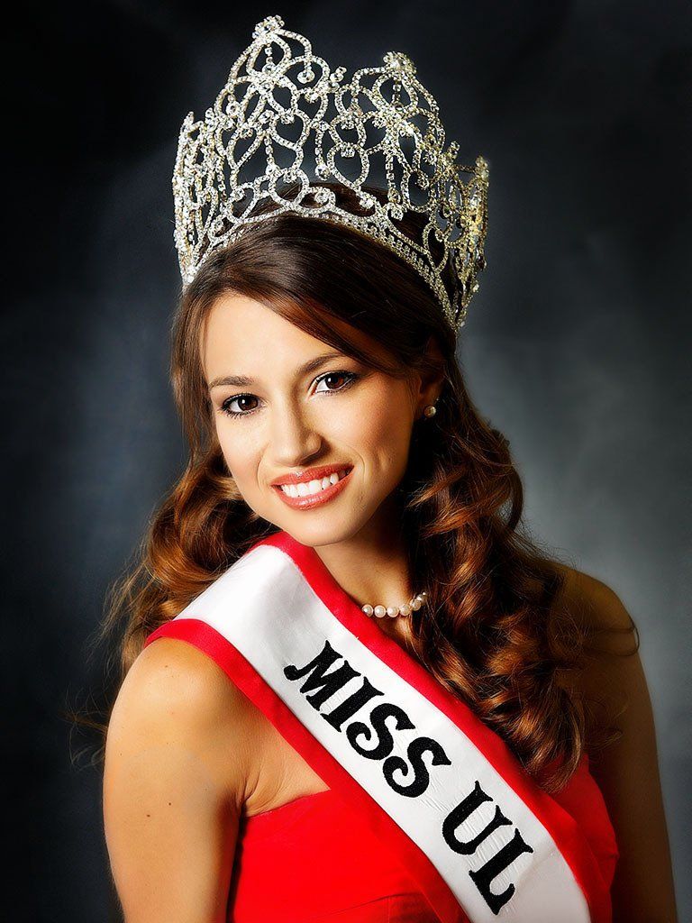 A woman wearing a crown and a sash that says miss ul